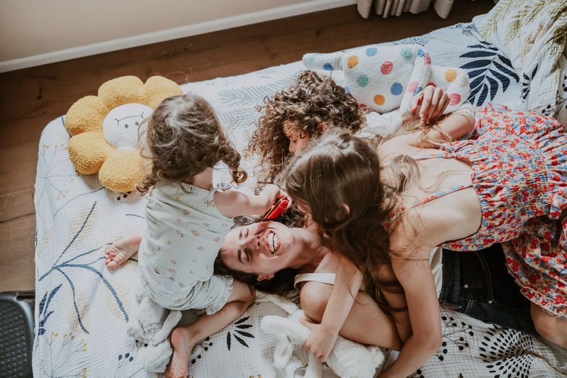 אמא והבנות מתגלגלות על המיטה
